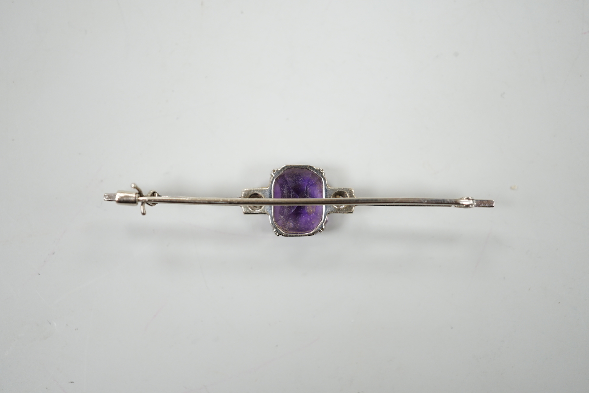 A 9ct white metal, amethyst and diamond set three stone bar brooch, 56mm, gross weight 3.7 grams, with original 1950's receipt.